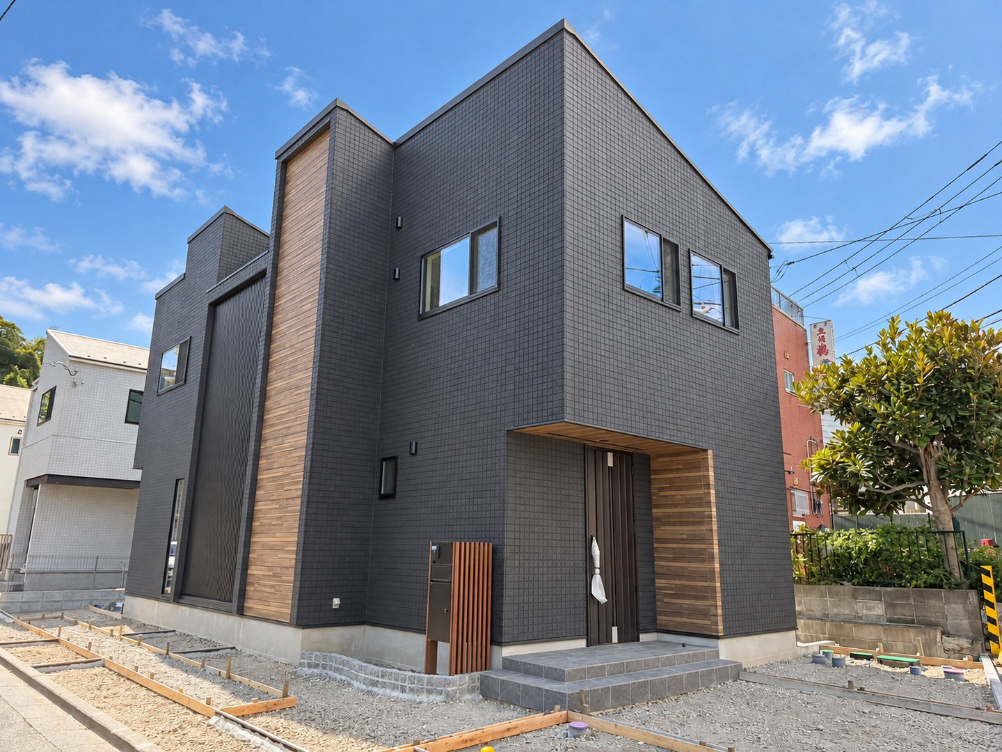 ダークカラーの外壁と木目調の玄関まわりを組み合わせたA号棟の外観